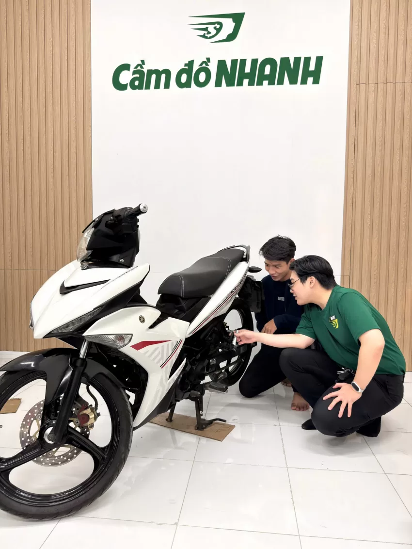 Nhân viên Cầm đồ Nhanh kiểm tra xe máy cùng khách tại cửa hàng